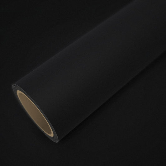 Rouleau de vinyle noir mat posé sur une feuille du même vinyle
